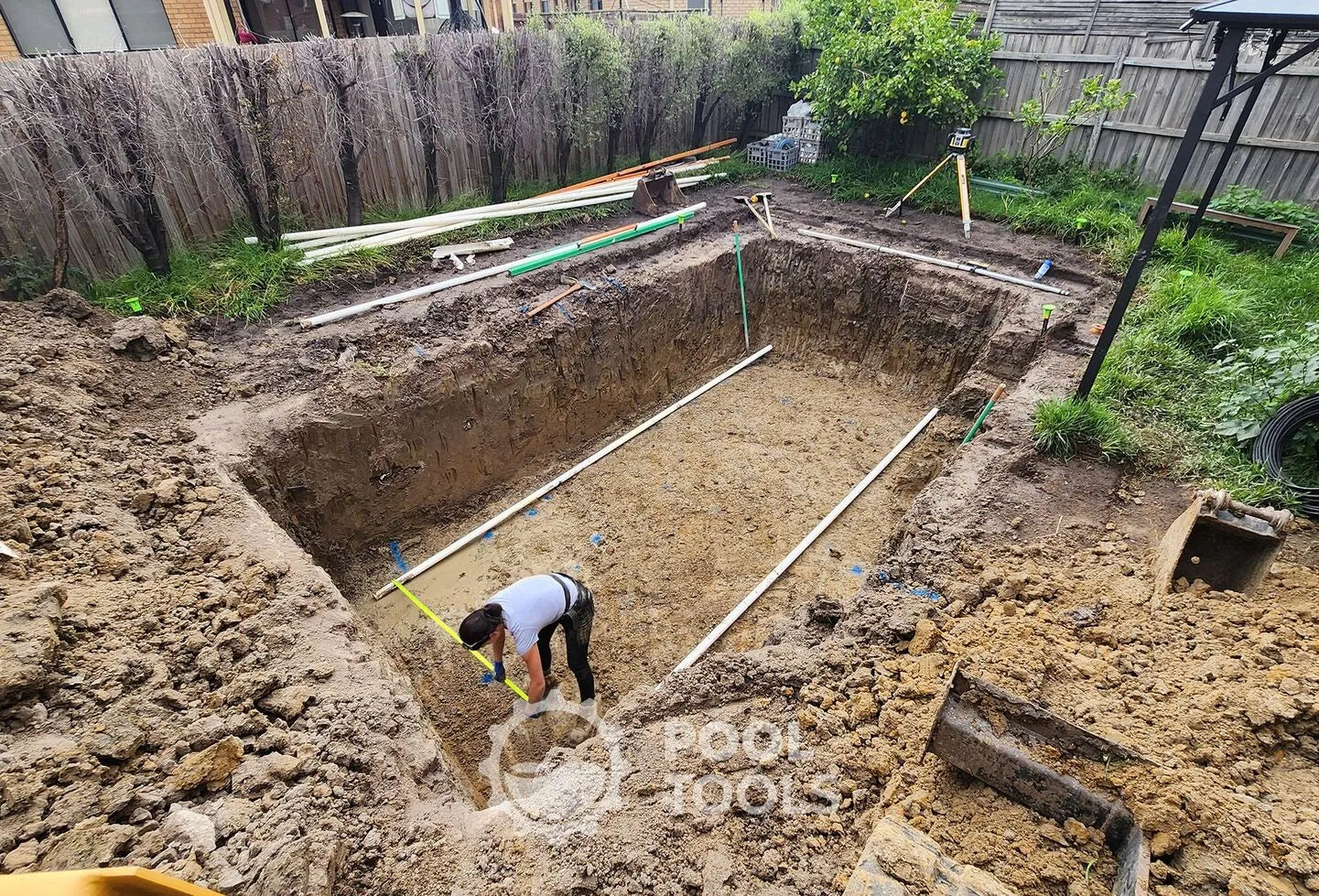 Person working on a pool foundation in a backyard
