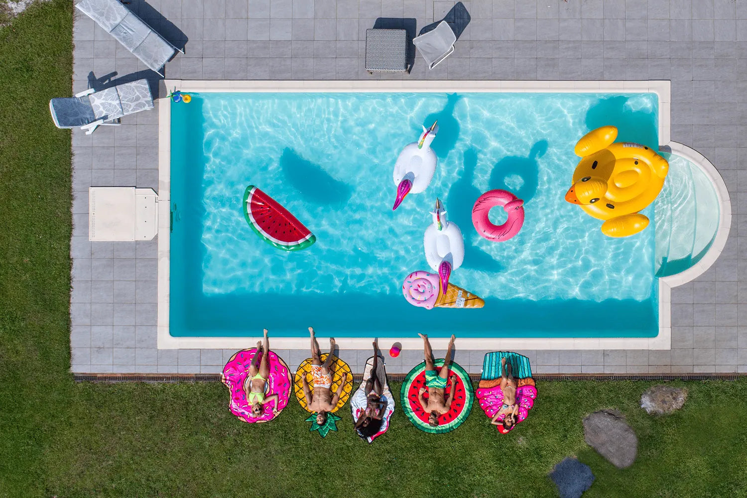 Aerial view of a pool with people on inflatable rings and pool toys.