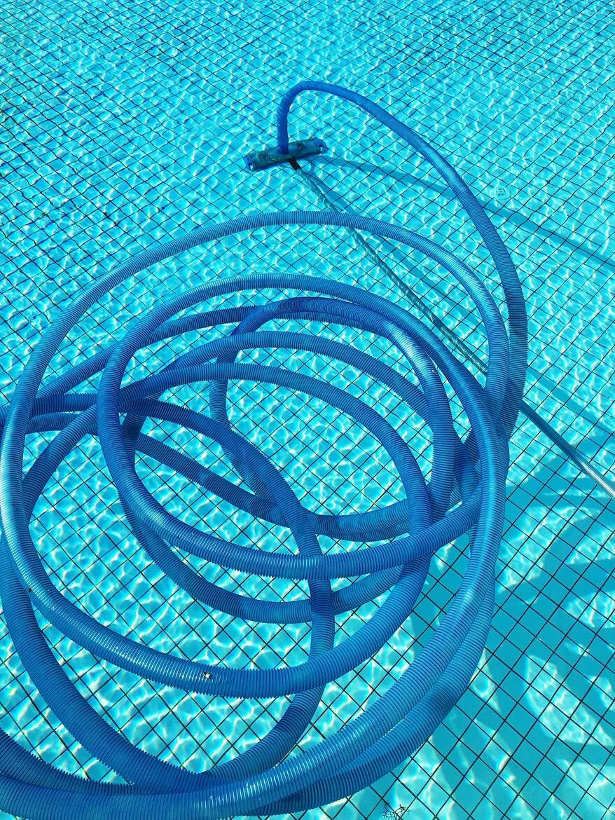 Coiled blue pool vacuum hose on a pool surface