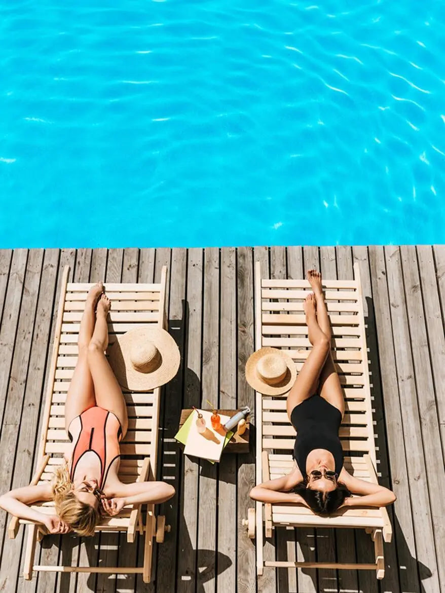 Two women relaxing on lounge chairs by a pool